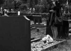 Woman standing in front of a grave site in black and white.