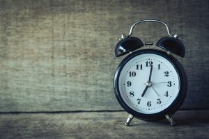 Black analogue alarm clock on wooden table
