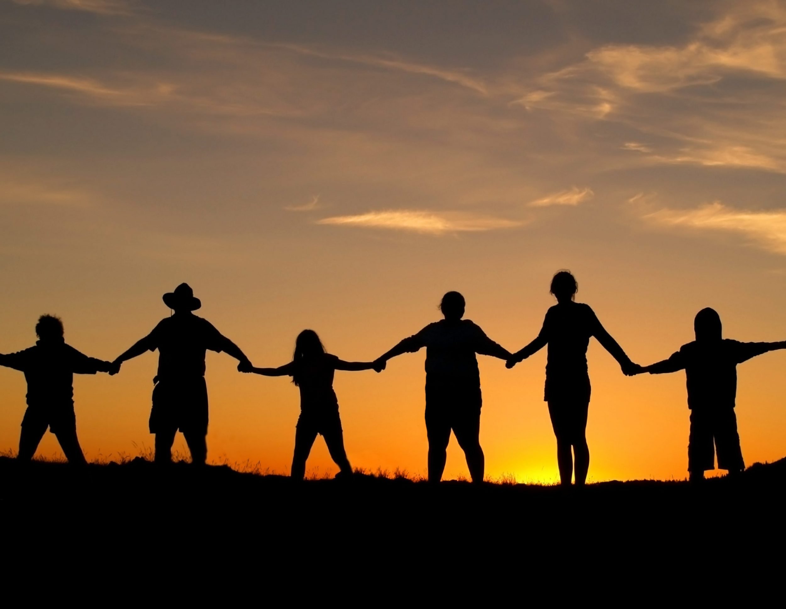 Multi-aged family holding hands at sunset