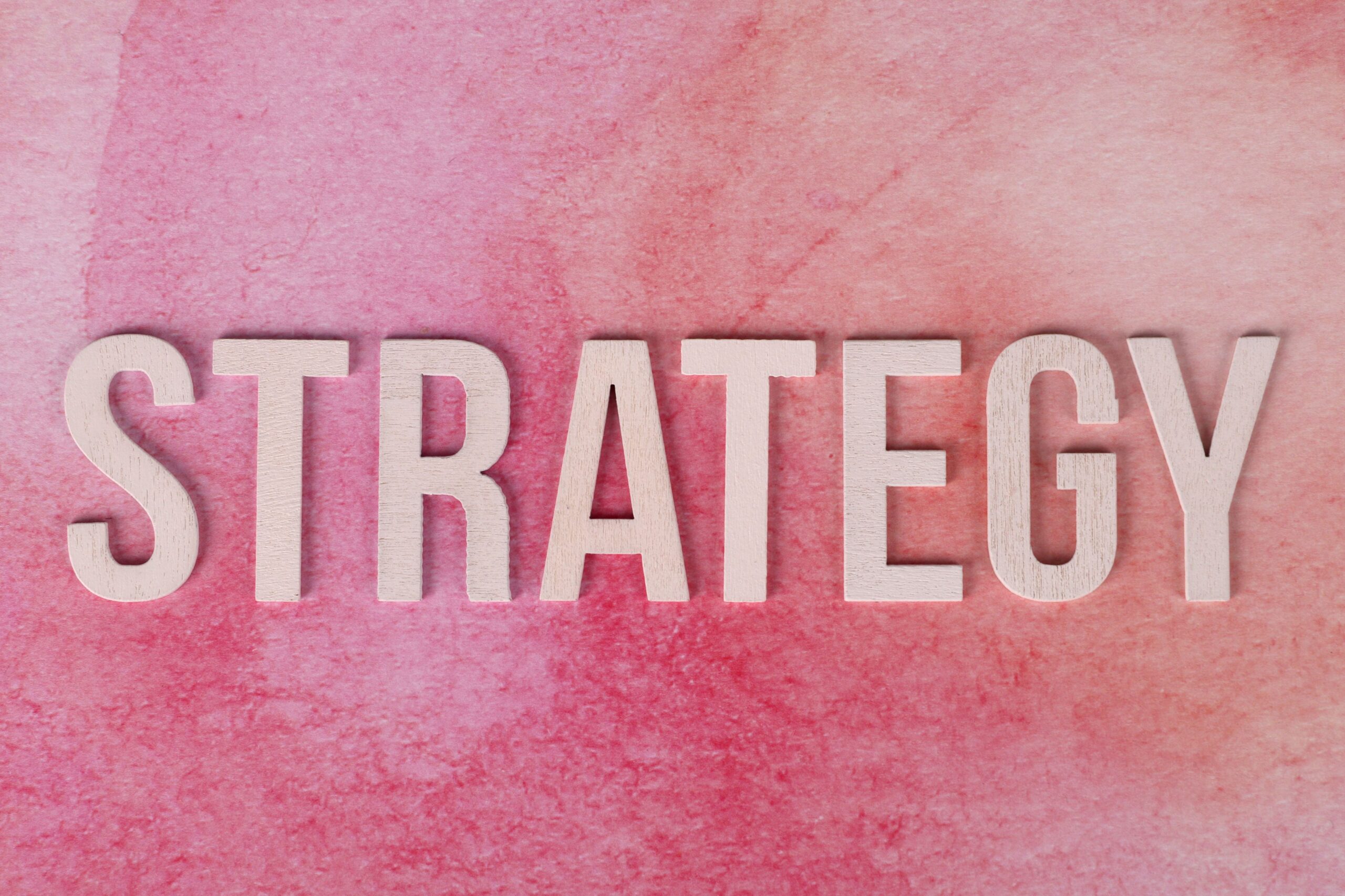 The word "strategy" in cream block letters on a pink background